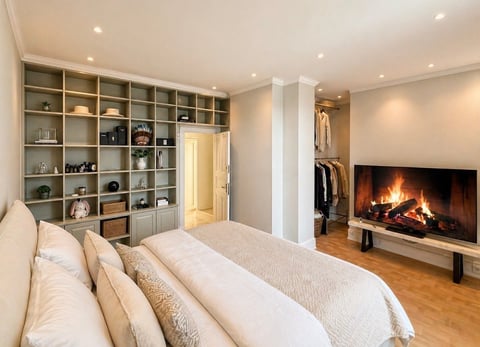Luxury bedroom with fireplace, built-in shelving, walk-in closet, and hardwood floors